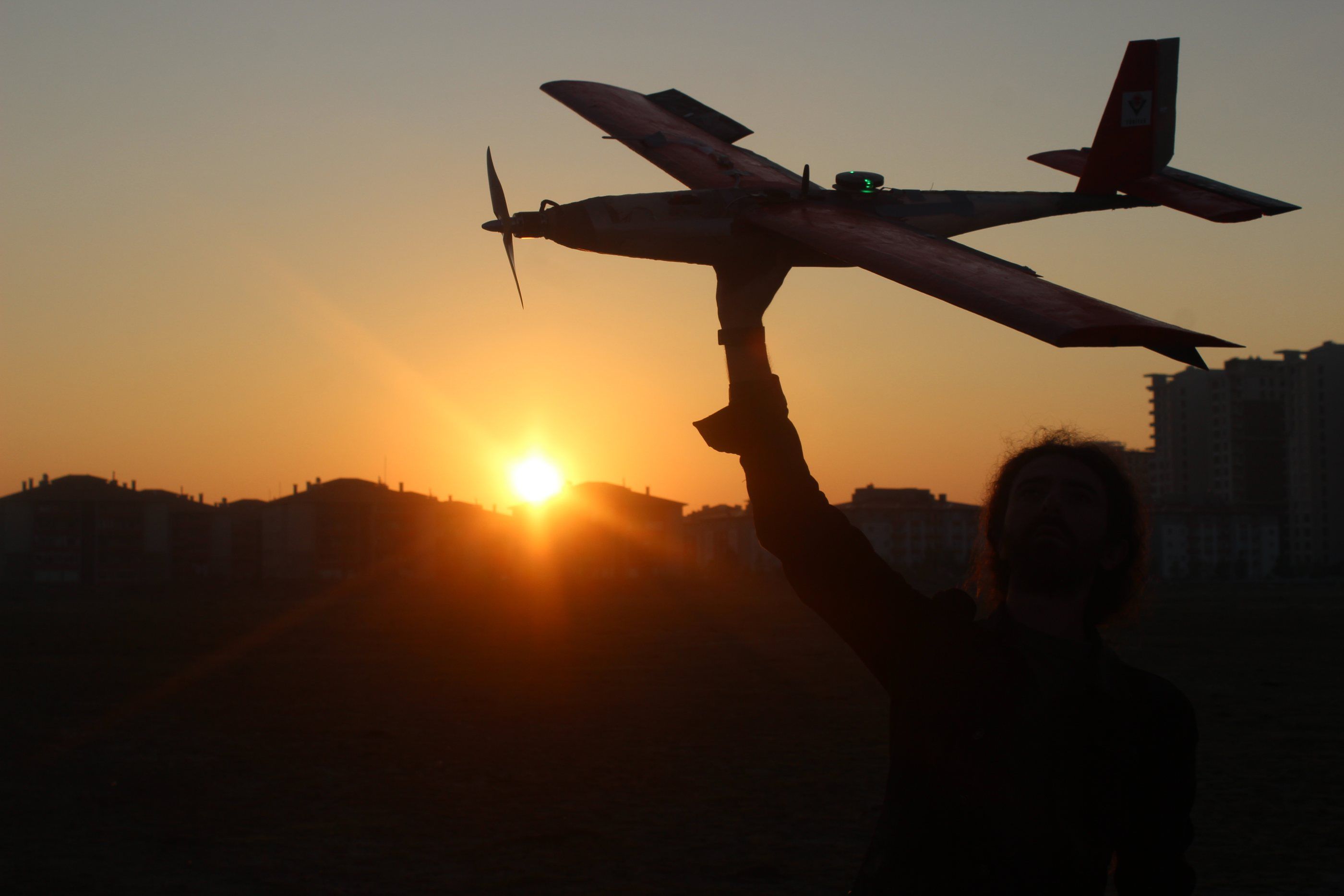 A fixed-wing UAV held up against the sunset at TEKNOFEST 2022